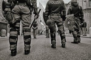 Black and white image of police officers with tactical gear during street patrol in an urban setting.