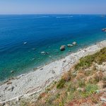 Stunning seaside view from Riomaggiore, highlighting clear blue waters and rocky beach.