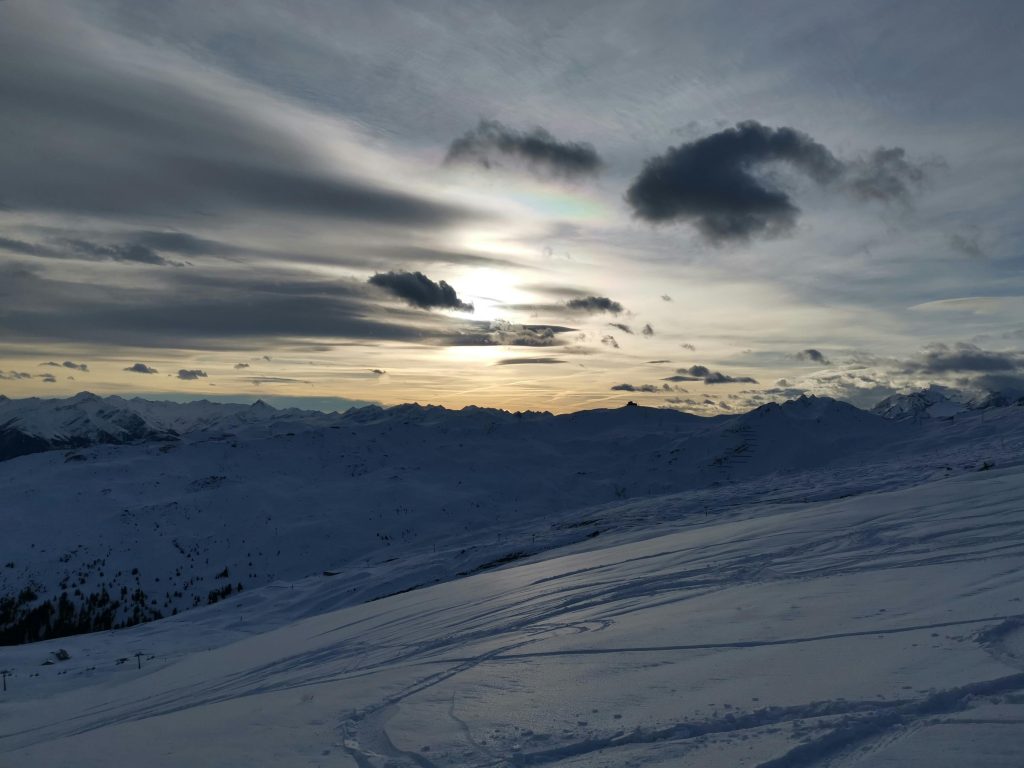Beautiful snowy mountain landscape at sunset with dramatic clouds and serene ambiance.