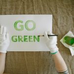 Overhead view of go green poster creation with paint and gloves on natural fabric background.