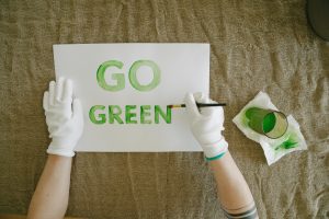 Overhead view of go green poster creation with paint and gloves on natural fabric background.