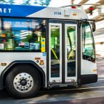 A city bus from TriMet transit system speeds through an urban street during the day.