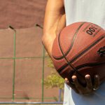 Hand holding a basketball on an outdoor court, ready for play.