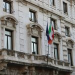 Elegant Renaissance architecture in Milan, featuring Italian and EU flags.