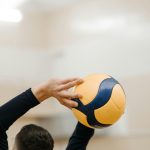 Close-up of a volleyball player holding a ball overhead, ready to serve in a gymnasium.