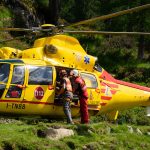 Emergency rescue team preparing helicopter in mountainous rural area.
