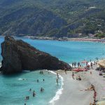 Stunning summer beach scene in Cinque Terre with turquoise waters and colorful umbrellas.