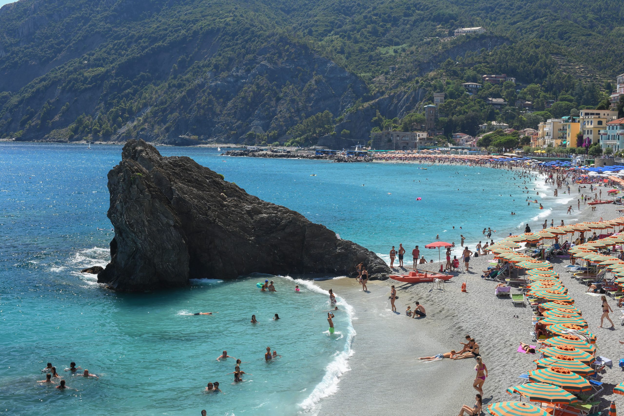Stunning summer beach scene in Cinque Terre with turquoise waters and colorful umbrellas.