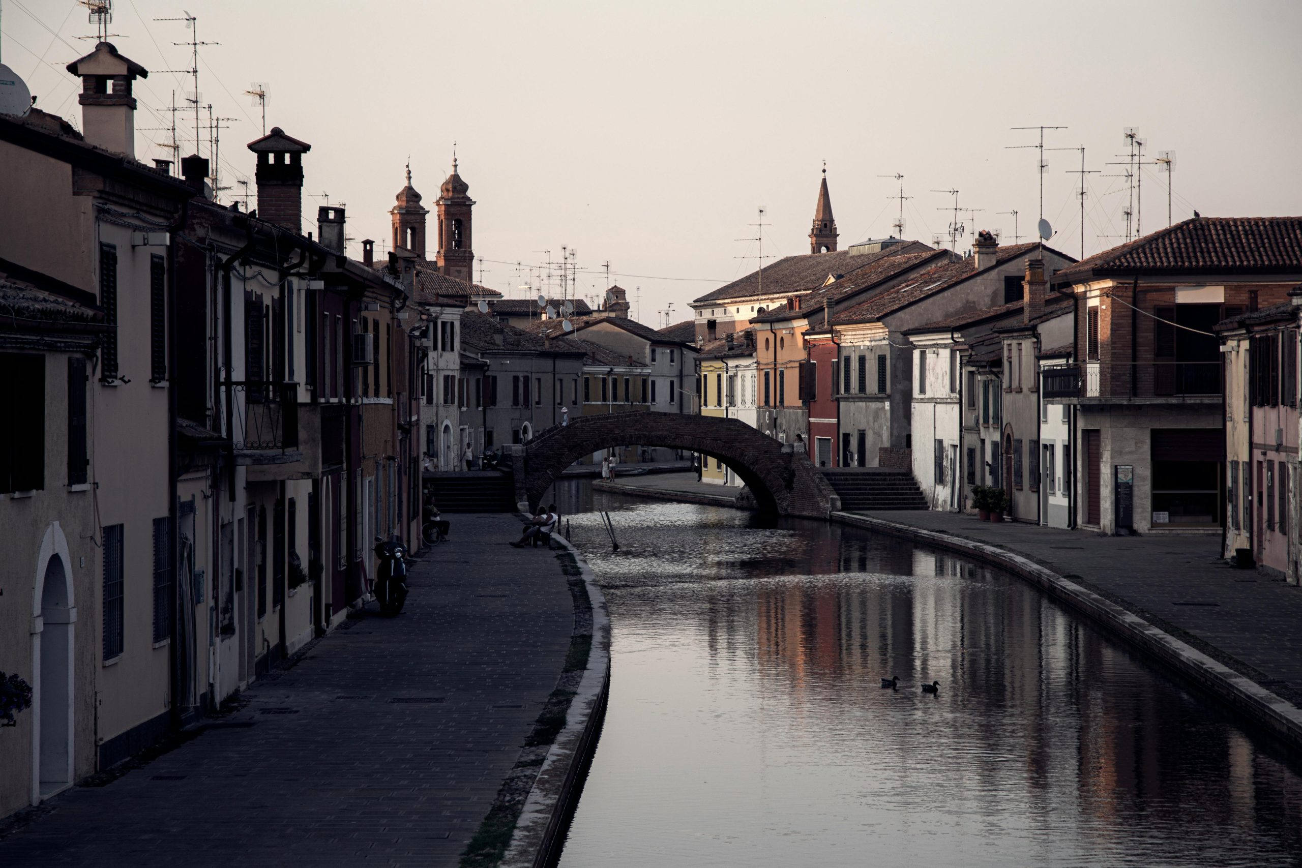 Charming canal scene in Comacchio, Italy featuring historical architecture and a serene water reflection.