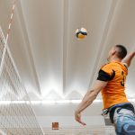 Dynamic shot of a male volleyball player spiking the ball during an indoor match.